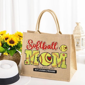 以下が含まれることがあります： 赤と黄色の「Softball MOM」の文字とソフトボールのグラフィックが入った、ベージュ色のジュートトートバッグ。バッグには「LIKE A NORMAL MOM BUT LOUDER & PROUDER」の文字も入っています。バッグには2つのベージュ色のハンドルが付いています。