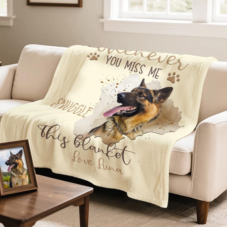 K&ouml;nnte beinhalten: Cremefarbene Decke mit einem Design eines Deutschen Sch&auml;ferhundes. Der Text auf der Decke lautet: &bdquo;Whenever you miss me, snuggle this blanket, Love Luna.&ldquo; Ein gerahmtes Foto des Hundes befindet sich auf einem Tisch vor der Decke.