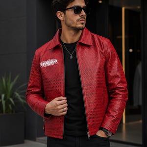 Peut inclure: Une veste rouge vif présentant un motif texturé inspiré des reptiles sur toute la surface. La veste est dotée d'un col classique, d'une fermeture éclair intégrale sur le devant et d'un détail graphique blanc distinct sur la poitrine droite.
