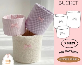 Peut inclure: Trois seaux de vanité en rose, vichy lavande et textures sherpa crème, chacun orné d'un nœud rose. L'image comprend un dessin au trait des seaux et le texte "VANITY BUCKET", "3 SIZES", "PDF PATTERN" et "BEGINNER FRIENDLY".