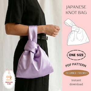 May include: A lavender Japanese knot bag made of satin fabric. The bag is held by a person wearing a black outfit. The image includes text that says "Japanese Knot Bag", "One Size", "PDF Pattern", "Beginner Friendly", and "instant download".