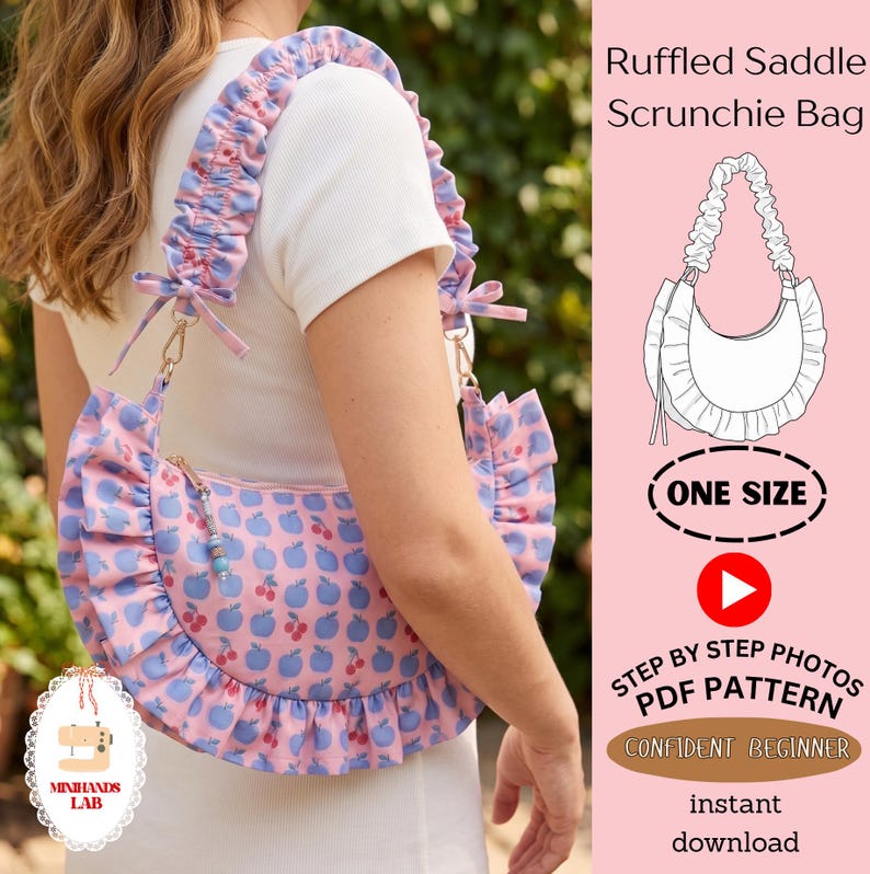 May include: A pink shoulder bag with a blue apple and red cherry print, featuring a ruffled trim and a gathered scrunchie-style strap. The bag includes a zipper closure with a beaded pull. Text on the image reads Ruffled Saddle Scrunchie Bag.