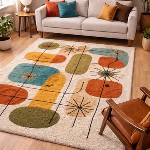 May include: A cream-coloured area rug with a mid-century modern design. The rug features geometric shapes in orange, yellow, teal, and green, connected by black lines. The rug is placed in a living room with a sofa and wooden chair.