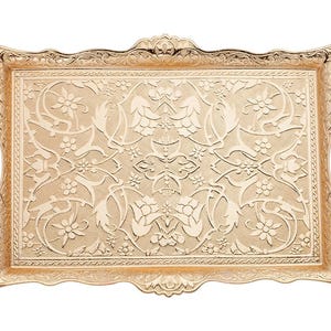 Pode incluir: Uma bandeja retangular dourada com padr&otilde;es florais e de folhas ornamentados. A bandeja tem duas al&ccedil;as curvas e uma borda decorativa. A superf&iacute;cie &eacute; coberta por um design em relevo detalhado. A bandeja &eacute; de metal.