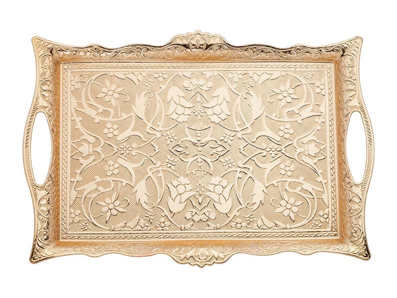 Pode incluir: Uma bandeja retangular dourada com padr&otilde;es florais e de folhas ornamentados. A bandeja tem duas al&ccedil;as curvas e uma borda decorativa. A superf&iacute;cie &eacute; coberta por um design em relevo detalhado. A bandeja &eacute; de metal.