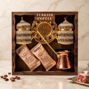 May include: A wooden box set containing Turkish coffee essentials. Includes two ornate coffee cups with jewel accents, a golden saucer, a copper coffee pot, two coffee packets, and a long-handled spoon. The box is labeled "TURKISH COFFEE".