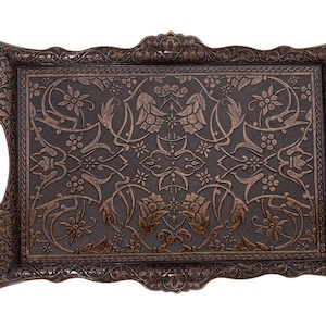 Pode incluir: Bandeja retangular decorativa marrom escuro com um intrincado padr&atilde;o floral e de folhas. A bandeja apresenta uma superf&iacute;cie texturizada e al&ccedil;as integradas. As bordas e as al&ccedil;as t&ecirc;m um design detalhado em relevo. Uma pe&ccedil;a decorativa.