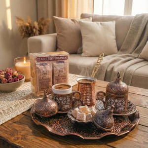 Peut inclure: Un service à café en cuivre orné, comprenant des tasses, des soucoupes, une petite cafetière et un plateau de service. Une boîte de café et un petit plat de loukoums sont également présents. Le texte sur la boîte indique "12 ADET TEK FINCANLIK".