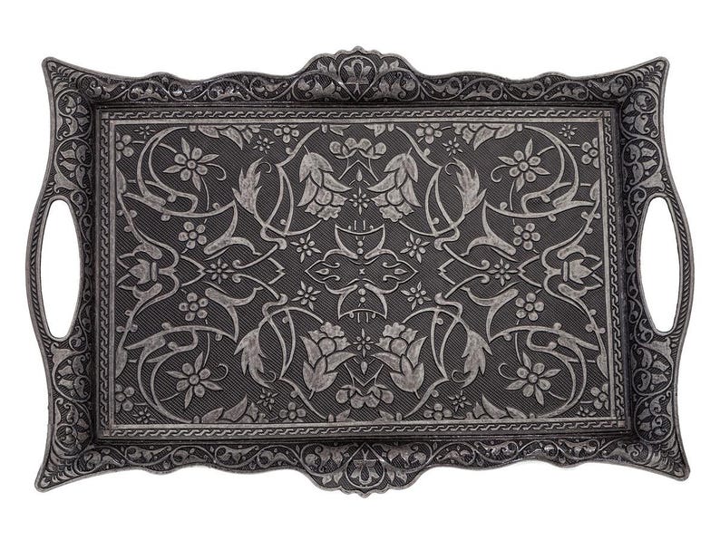 Pode incluir: Bandeja decorativa retangular cinza escuro com um padr&atilde;o floral e de folhas. A bandeja tem al&ccedil;as integradas e uma borda detalhada. O design &eacute; sim&eacute;trico e apresenta flores e folhagens.