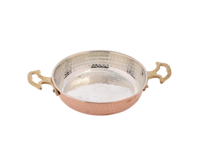 Puede incluir: Una sart&eacute;n de color cobre, con acabado martillado, interior plateado y dos asas de lat&oacute;n. La sart&eacute;n tiene forma redonda y poco profunda, adecuada para cocinar y servir. Las asas son curvas y decorativas.