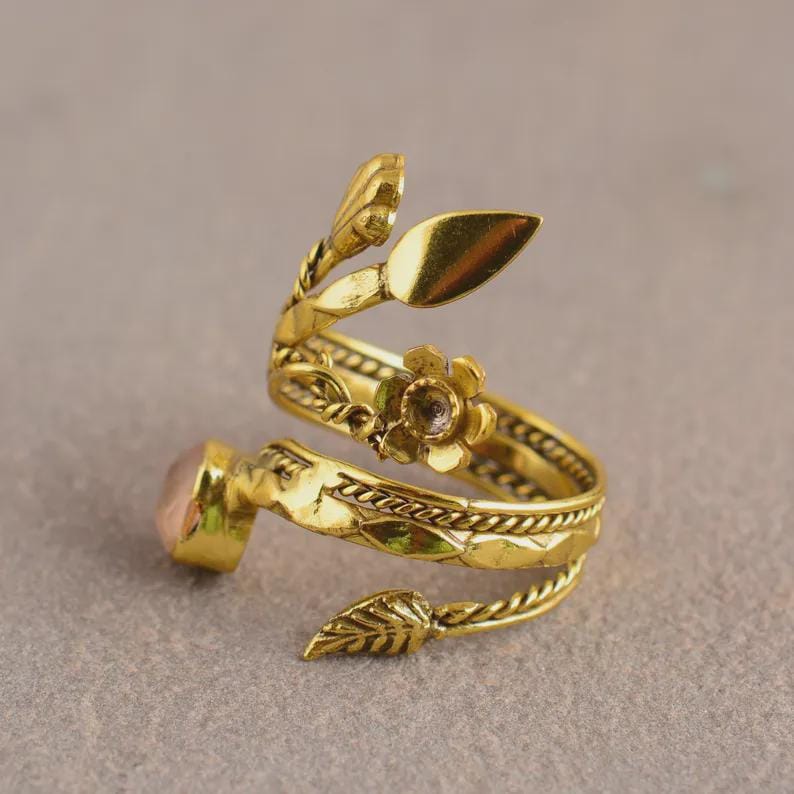 Peut inclure: Une bague dor&eacute;e r&eacute;glable avec un motif floral et de feuilles. La bague pr&eacute;sente une pierre pr&eacute;cieuse rose et est fabriqu&eacute;e en forme de spirale. La conception de la bague comprend des fleurs et des feuilles.