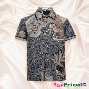 May include: Short-sleeved button-down shirt with a dark blue floral pattern and decorative paisley and floral accents in gray, brown, and black. The shirt has a black collar and trim.