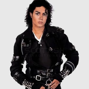 Puede incluir: Chaqueta negra con múltiples hebillas, correas y detalles plateados. La chaqueta tiene un cuello alto y se usa sobre una camisa blanca. La imagen presenta a una persona con cabello oscuro. La chaqueta es un diseño Scottish Traditional.