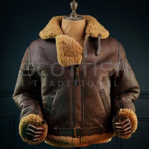 Pu&ograve; includere: Giacca bomber in pelle marrone con colletto e polsini in montone. La giacca ha una chiusura a zip frontale, una cintura in vita e il testo "SCOTTS TRADITIONAL" &egrave; visibile. La giacca &egrave; esposta su un manichino.