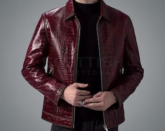 May include: A burgundy leather jacket with a crocodile skin texture. The jacket has a zip closure, a collared neckline, and brown trim. The sleeves are long, and the jacket appears to be a medium weight.