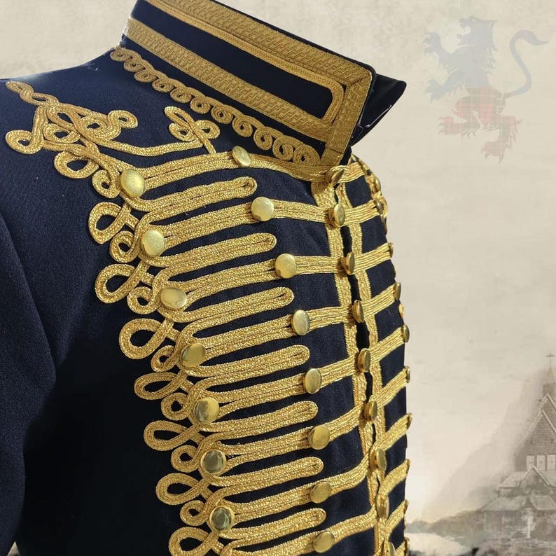 K&ouml;nnte beinhalten: Marineblaue Jacke im Milit&auml;rstil mit goldfarbenen Stickereien und Kn&ouml;pfen. Die Jacke hat aufwendige goldfarbene Verzierungen um Kragen, Manschetten und Vorderseite, was ihr ein formelles und verziertes Aussehen verleiht. Die Kn&ouml;pfe sind ebenfalls goldfarben.
