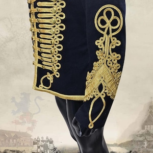 K&ouml;nnte beinhalten: Marineblaue Jacke mit aufwendiger Goldstickerei und goldenen Kn&ouml;pfen. Die Jacke hat detaillierte goldene Verzierungen an den R&auml;ndern und &Auml;rmeln, was einen k&ouml;niglichen Eindruck erweckt. Das Design erinnert an historische Milit&auml;rkleidung.