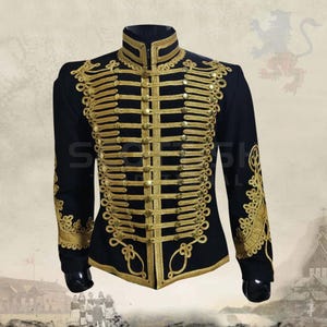 K&ouml;nnte beinhalten: Schwarze Jacke im Milit&auml;rstil mit goldener Stickerei und Kn&ouml;pfen. Die Jacke hat einen hohen Kragen und aufwendige goldene Verzierungen auf Brust und &Auml;rmeln. Ein formelles Kleidungsst&uuml;ck mit historischer &Auml;sthetik.