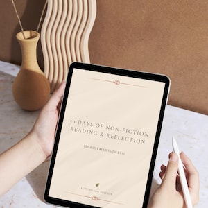 Op de afbeelding: Een digitale tablet met de tekst "30 DAGEN NON-FICTIE LEZEN & REFLECTIE" en "HET DAGELIJKSE LEESJOURNAAL". De tablet wordt door handen vastgehouden, met een stylus in de buurt. De achtergrond omvat een vaas met gedroogde bloemen en een decoratief houten stuk.