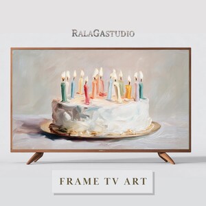 May include: A framed TV art piece featuring a painting of a birthday cake with lit candles. The cake is white with colorful candles. The frame is brown, and the text "RALAGASTUDIO" is at the top. The text "FRAME TV ART" is at the bottom.