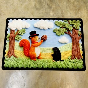 May include: An embroidered picture depicting a squirrel in a top hat presenting a pinecone to a mole. The scene includes trees, clouds, and a grassy field, framed by a black border. The squirrel has orange fur and a white belly.