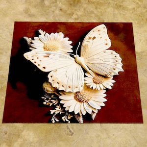 May include: A wooden artwork depicting a butterfly and daisies. The butterfly is cream-coloured with detailed wing patterns. The daisies have cream petals and tan centres. The background is a dark reddish-brown square.