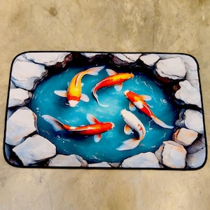 May include: Rectangular mat depicting a pond scene with five koi carp. The fish are orange, red, and white, swimming in blue water surrounded by white rocks. The mat has a black border.
