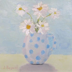May include: An oil painting of a bouquet of white daisies with yellow centers in a light blue polka-dotted vase. The background is a soft light blue, and the vase sits on a pale yellow surface. The artist's signature is in the bottom left corner.