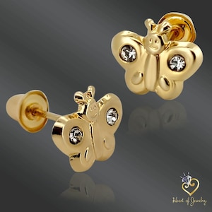 May include: A pair of gold-coloured butterfly stud earrings. Each earring features a butterfly design with clear, sparkling accents. The earrings have a post and backing for secure wear. The image is set against a dark background.