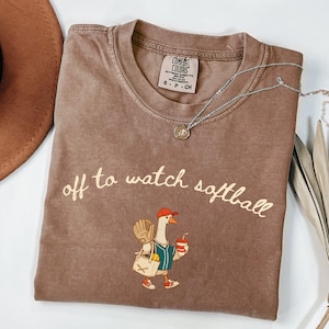 Funny softball fan t shirt design with cute goose character carrying softball gear and off to watch softball text for game day supporters