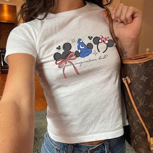 Disney baby tee featuring Mickey and Minnie inspired mouse ears, magic hat and bow design with some imagination huh text for Disney trip outfit