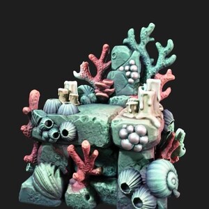 Pode incluir: Uma peça de terreno subaquático em miniatura com uma plataforma central de pedra adornada com ramos de coral esculpidos em tons de rosa e azul-petróleo, várias conchas e grupos de cracas com uma textura rochosa e desgastada.