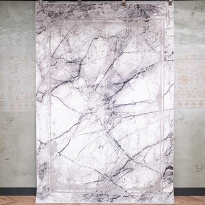 May include: A rectangular area rug featuring a white and light grey marble pattern with dark grey veining. The design includes a solid light grey border frame surrounding the central marble motif, creating a clean and structured visual appearance.