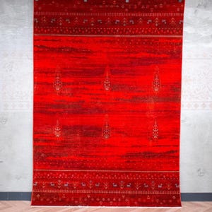 May include: A rectangular area rug featuring a vibrant red background with horizontal bands of dark, mottled texture. The rug displays a repeating pattern of small, intricate botanical motifs in the centre and decorative geometric borders.
