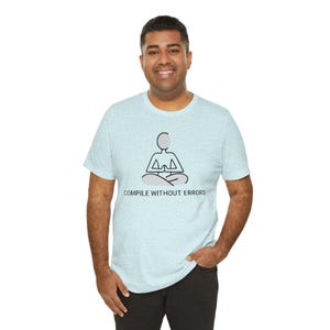 May include: Pale blue t-shirt featuring a meditating figure graphic and the text "COMPILE WITHOUT ERRORS" in black. The shirt is made of a soft, comfortable material.