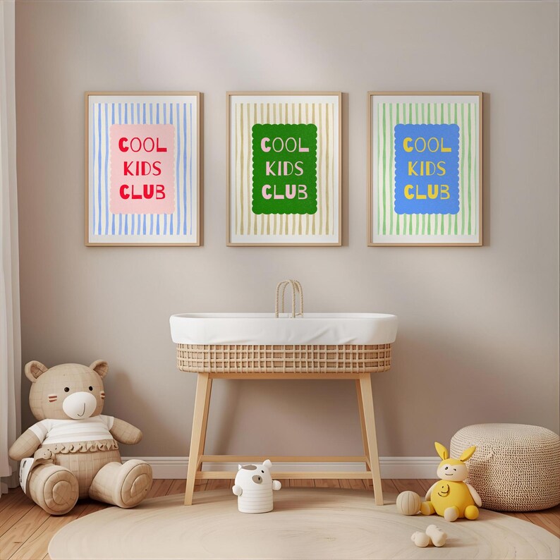 K&ouml;nnte beinhalten: Drei gerahmte Drucke mit dem Text "COOL KIDS CLUB". Die Drucke befinden sich &uuml;ber einer Wickelkommode und sind von Spielzeug umgeben. Die Drucke haben einen rosa, gr&uuml;nen und blauen Hintergrund. Die Rahmen sind hellbraun.