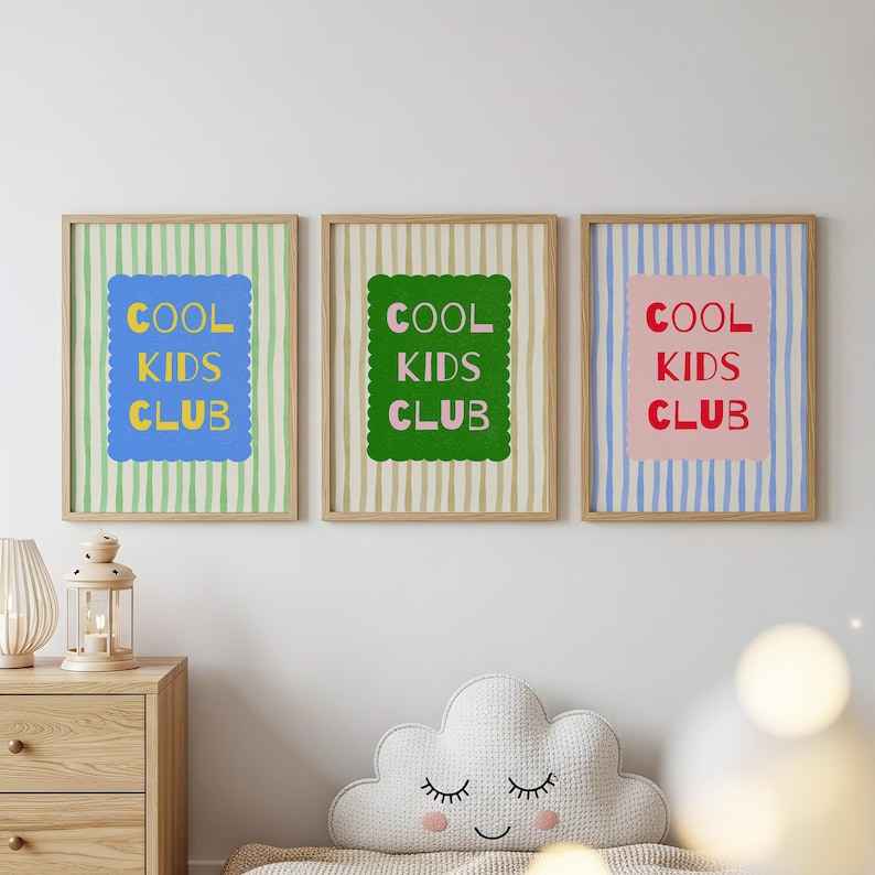K&ouml;nnte beinhalten: Drei gerahmte Drucke mit dem Text "COOL KIDS CLUB". Jeder Druck hat ein anderes Farbschema: blau, gr&uuml;n und rosa. Der Hintergrund jedes Drucks weist vertikale Streifen auf. Die Rahmen sind hellbraun.