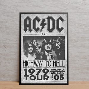 May include: Monochrome poster of the band AC/DC. The poster displays the band's logo, the word "LIVE", "HIGHWAY TO HELL", "1979 TOUR", and the date and location of a concert in Oakland, CA.