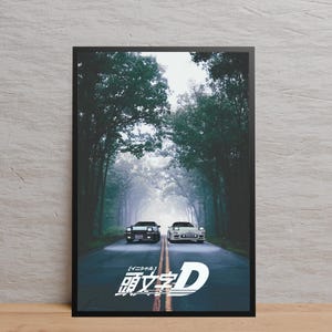 Könnte beinhalten: Gerahmter Druck mit zwei Sportwagen auf einer von Bäumen gesäumten Straße. Die Autos sind schwarz und weiß, mit eingeschalteten Scheinwerfern. Japanischer Text und ein stilisiertes 'D'-Logo vor nebligem Hintergrund.