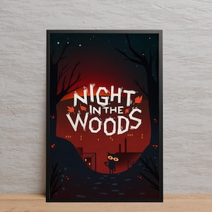 May include: A framed art print with the text "NIGHT IN THE WOODS" in white, set against a dark red and black forest scene. A small black cat with yellow eyes is in the foreground.
