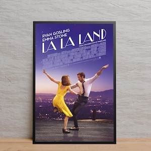 Puede incluir: Un póster enmarcado de la película "La La Land" con Ryan Gosling y Emma Stone. La imagen muestra a los actores bailando sobre un fondo de un horizonte urbano al anochecer. El título de la película está en letras blancas grandes.