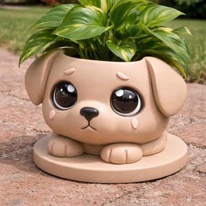 Puede incluir: Maceta con forma de perro de color beige con grandes ojos negros brillantes y una expresión triste. La maceta contiene una planta verde vibrante con acentos amarillos. La maceta se asienta sobre una base redonda a juego.