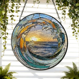 May include: Circular stained glass art piece depicting a wave with a sunset in the background. The wave is rendered in shades of blue, green, and gold, with a black metal frame and hanging chain. The artwork is approximately 12 inches in diameter.