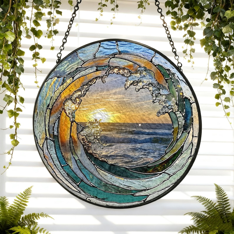 May include: Circular stained glass art piece depicting a wave with a sunset in the background. The wave is rendered in shades of blue, green, and gold, with a black metal frame and hanging chain. The artwork is approximately 12 inches in diameter.