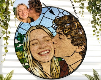 May include: A round stained glass art piece featuring a couple kissing. The artwork has a black metal frame and a chain for hanging. The image is a portrait of a smiling woman and a man kissing her cheek, with a smaller inset photo.