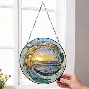 May include: A round stained glass window depicting a wave with a sunset scene. The wave is made of blue, green, and gold glass, with a black metal frame and chain for hanging. The sunset features orange and yellow hues.