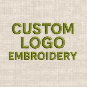 May include: A close-up shot of beige fabric with the words "CUSTOM LOGO EMBROIDERY" embroidered in green thread. The text is centered, with thick, bold letters, highlighting the embroidery.
