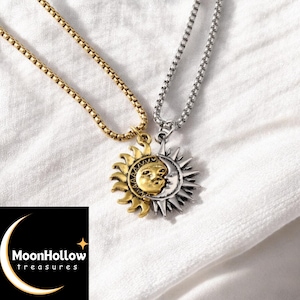 Può includere: Due collane abbinate con ciondoli a forma di sole e luna. Una collana ha una catena e un ciondolo color oro, l'altra ha una catena e un ciondolo color argento. I ciondoli sono collegati, con il sole e la luna che condividono un volto. Il logo MoonHollow treasures è in basso a sinistra.