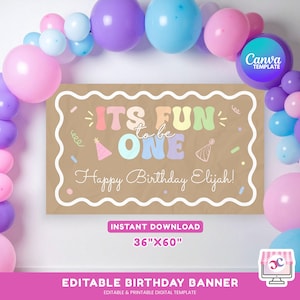 Puede incluir: Una pancarta de cumpleaños con el texto "ITS FUN to be ONE Happy Birthday Elijah!" en colores pastel. La pancarta es marrón con un borde blanco y está rodeada de globos rosas, morados y azules. La pancarta mide 91cm x 152cm.