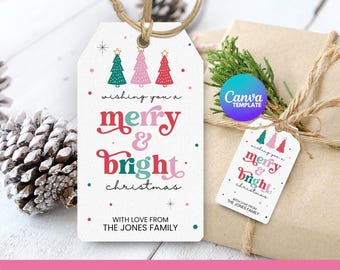 May include: A white Christmas gift tag with a festive design. The tag features the words "merry & bright christmas" in red and pink, with three Christmas trees at the top. The tag is tied with twine and is on a wrapped gift.